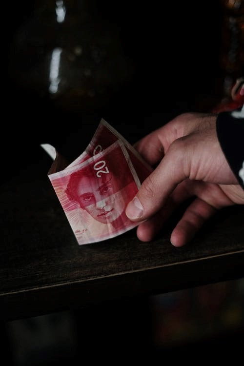 A person holding a 20 Israeli new shekel banknote-min